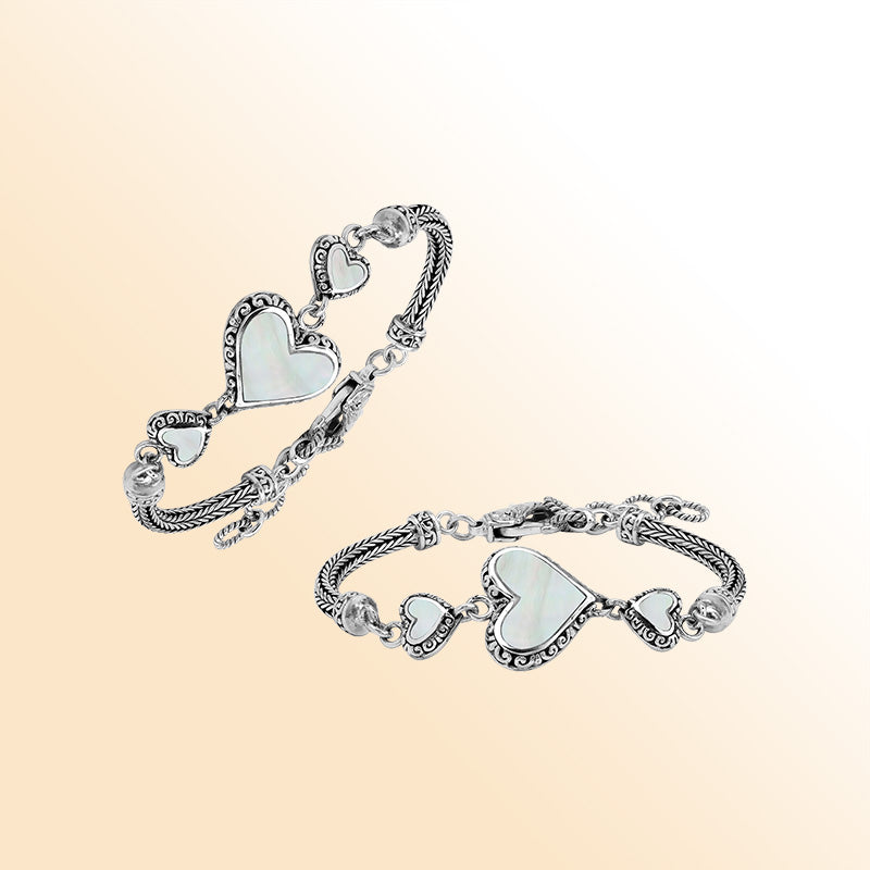 Handcrafted sterling silver bracelet featuring luminous Mother Of Pearl heart motifs, ornate Balinese scroll engravings, and a secure lobster lock for elegant, expressive, artisan-inspired everyday wear.