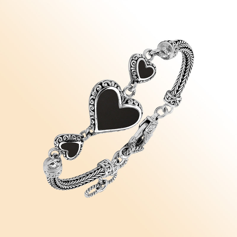 Handcrafted sterling silver bracelet featuring Black Shell heart motifs, intricate Balinese scroll engravings, and a secure lobster lock for bold, expressive, artisan-inspired everyday wear.
