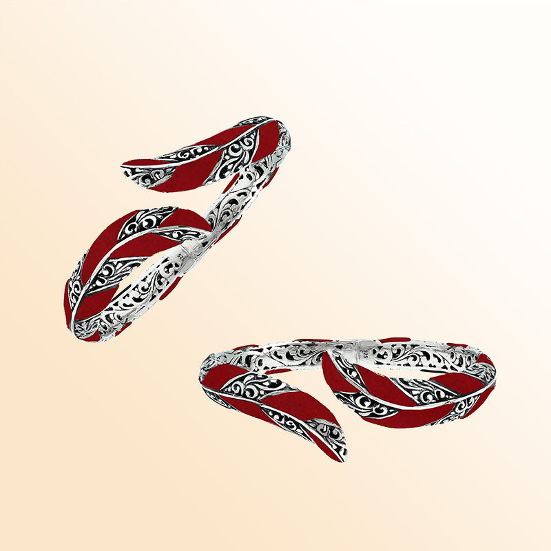 Handcrafted sterling silver feather-inspired bangle featuring vivid Red Coral inlays, ornate Balinese scroll engravings, and a secure hinge lock for expressive, artistic everyday elegance.