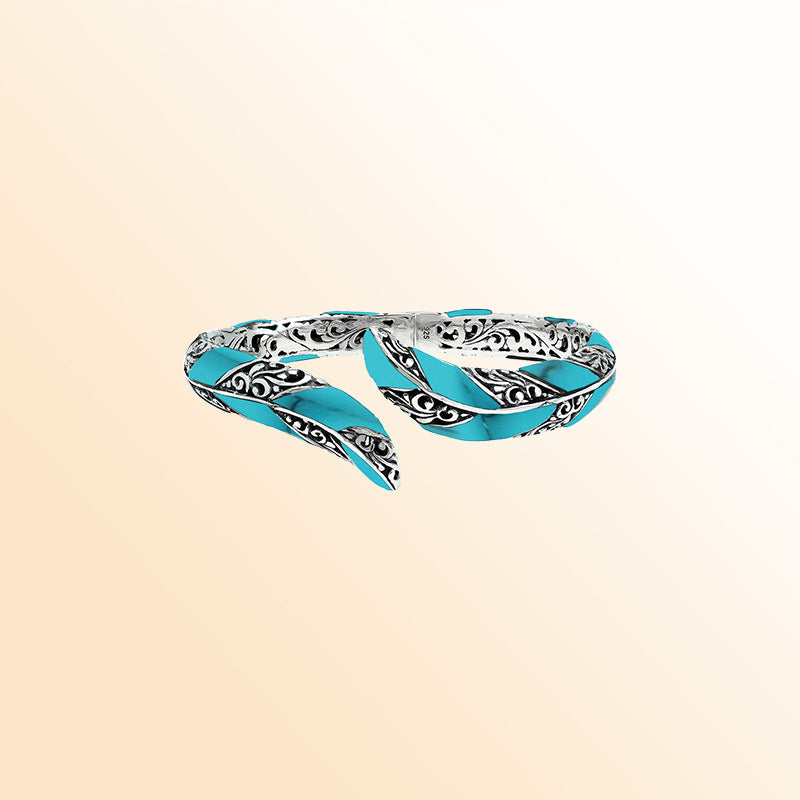 Handcrafted sterling silver feather-inspired bangle featuring vibrant Turquoise Shell inlays, intricate Balinese scroll engravings, and a secure hinge lock for colorful, expressive artisan wear.
