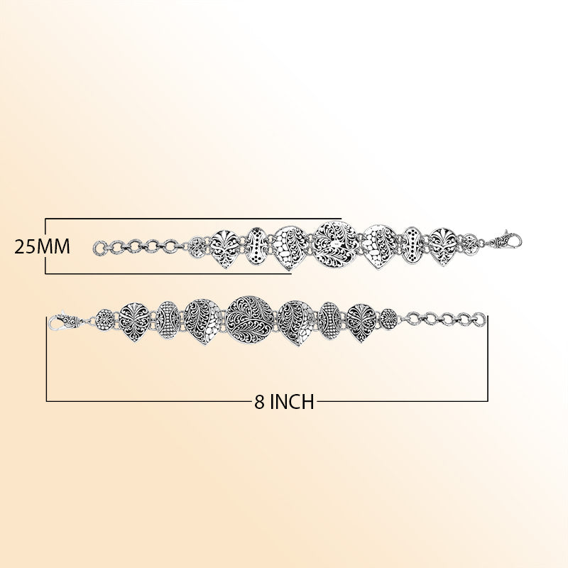 Handcrafted sterling silver link bracelet featuring carved Balinese scrollwork motifs across multiple shapes with oxidized details and a secure lobster lock closure.