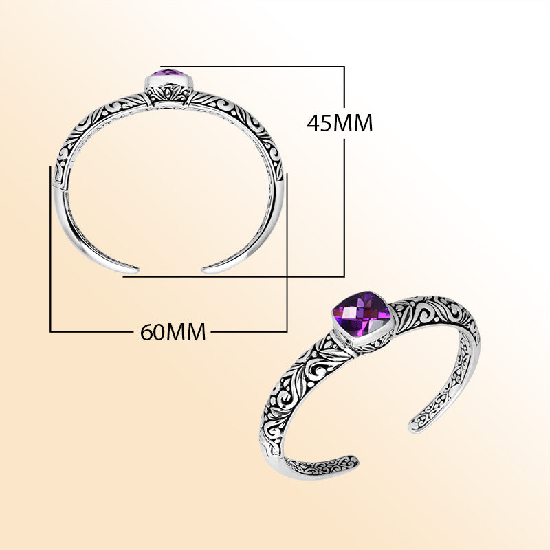 Handcrafted sterling silver bangle featuring a cushion-cut Amethyst Quartz gem, ornate Balinese scroll engravings, and a secure hinge lock for expressive artisan-inspired wear.