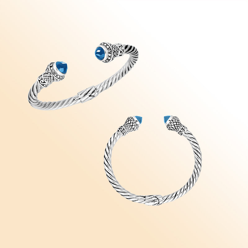 Handcrafted sterling silver cable cuff bracelet featuring sparkling faceted blue topaz quartz end caps, ornate Balinese detailing, and a secure hinge lock for daily elegance.