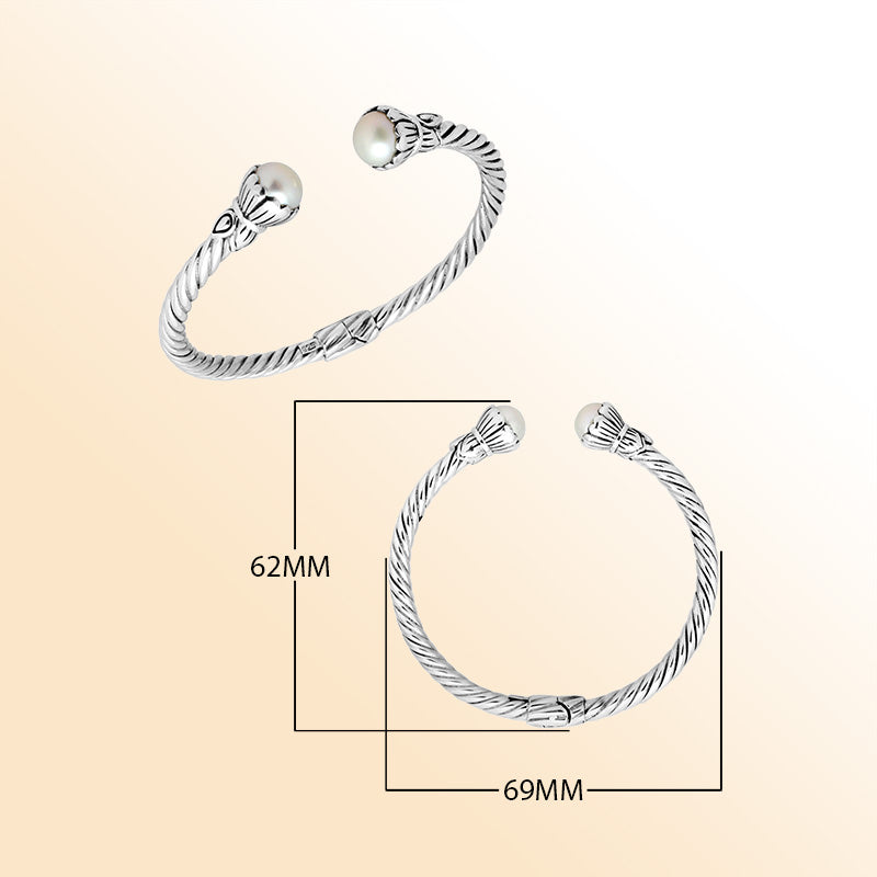 Handcrafted sterling silver cable cuff bracelet featuring smooth Mabe pearl end caps, sculpted detailing, and a secure hinge lock for timeless everyday elegance.