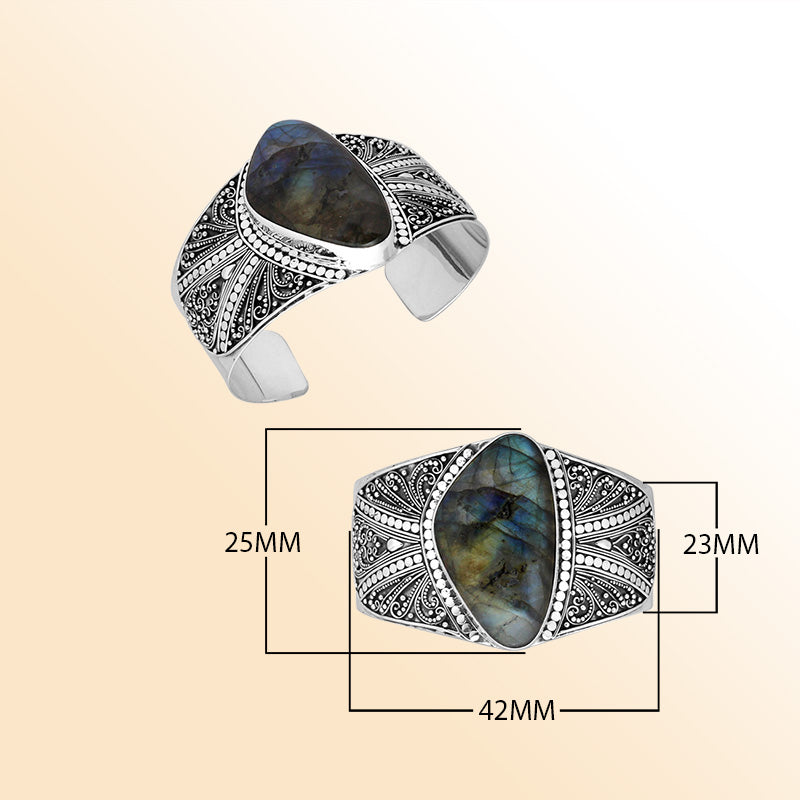 Sterling silver artisan cuff bracelet featuring a luminous labradorite stone framed by ornate Bali filigree patterns, designed for elegant statement jewelry lovers.
