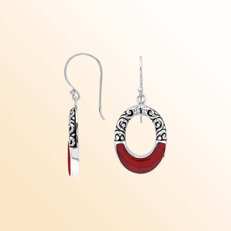 Handcrafted sterling silver dangle earrings showcasing vivid Red Coral inlay, elegant oval openings, ornamental scrollwork, contrasting oxidized accents, and graceful French ear wires.