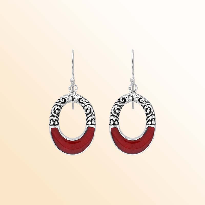 Handcrafted sterling silver dangle earrings showcasing vivid Red Coral inlay, elegant oval openings, ornamental scrollwork, contrasting oxidized accents, and graceful French ear wires.