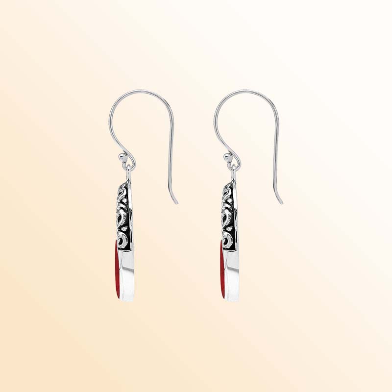 Handcrafted sterling silver dangle earrings showcasing vivid Red Coral inlay, elegant oval openings, ornamental scrollwork, contrasting oxidized accents, and graceful French ear wires.