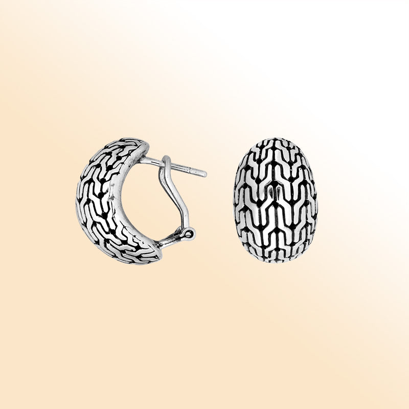 Artisan sterling silver omega-clip hoop earrings with raised oxidized pattern design.