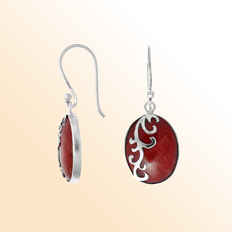Sterling silver artisan earrings featuring vivid oval red coral with a flowing wave-style overlay, crafted to create an expressive ocean-inspired look for elegant everyday wear.