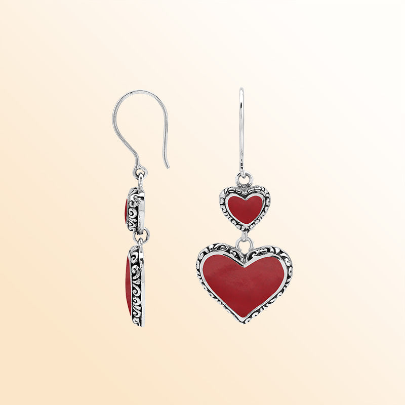 Sterling silver artisan earrings featuring vibrant red coral double hearts with ornate decorative borders, designed to create an expressive romantic look for elegant everyday wear.