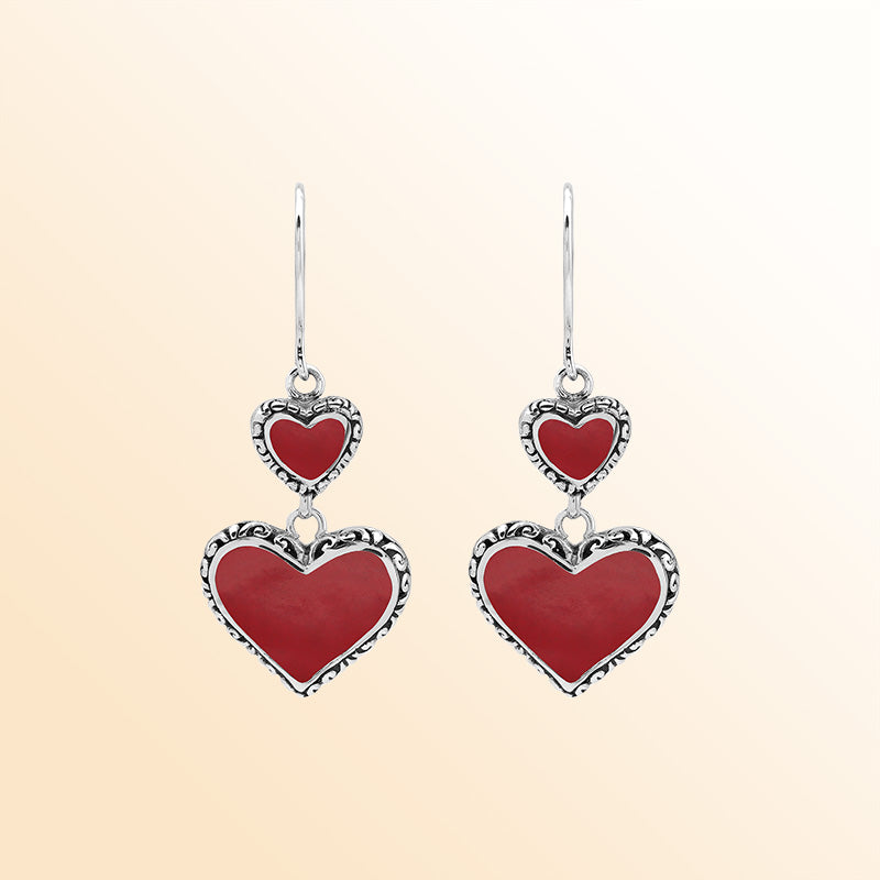 Sterling silver artisan earrings featuring vibrant red coral double hearts with ornate decorative borders, designed to create an expressive romantic look for elegant everyday wear.