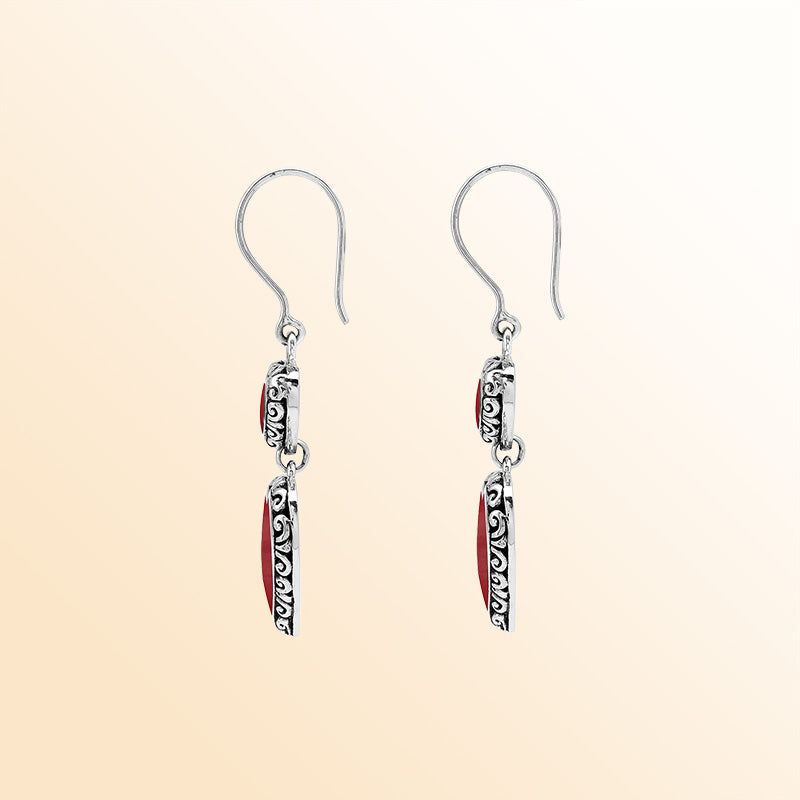Sterling silver artisan earrings featuring vibrant red coral double hearts with ornate decorative borders, designed to create an expressive romantic look for elegant everyday wear.