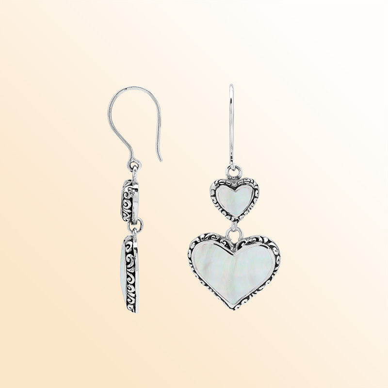 Sterling silver artisan earrings featuring luminous double mother of pearl hearts with ornate borders, designed to create a romantic and expressive look for elegant everyday wear.