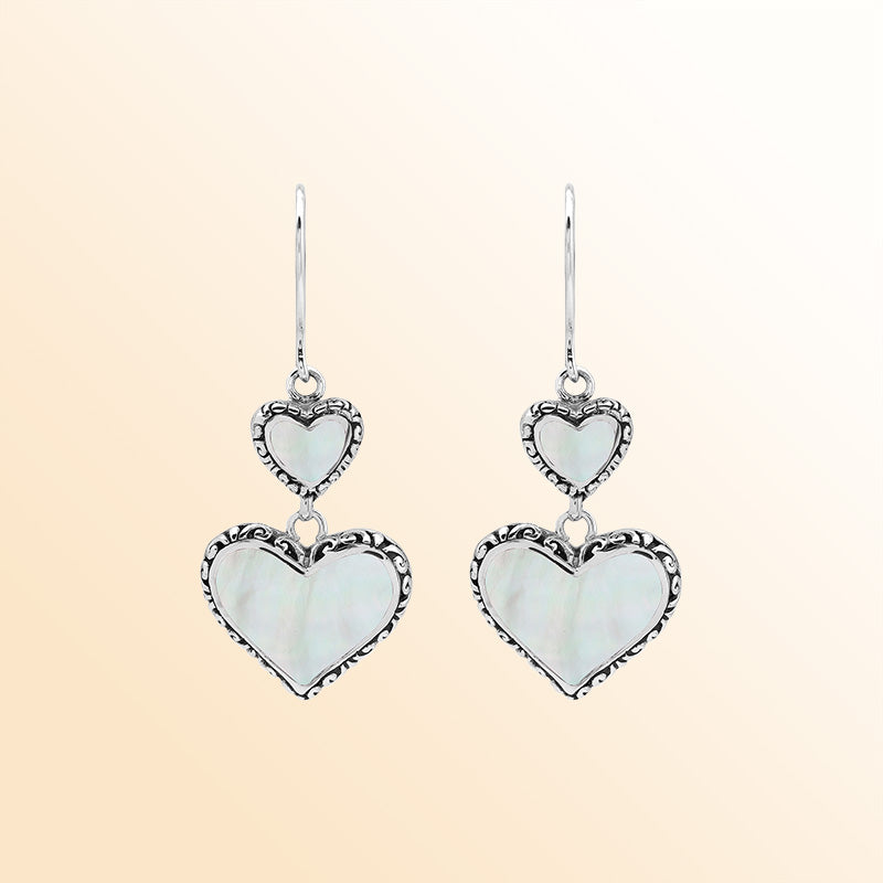 Sterling silver artisan earrings featuring luminous double mother of pearl hearts with ornate borders, designed to create a romantic and expressive look for elegant everyday wear.