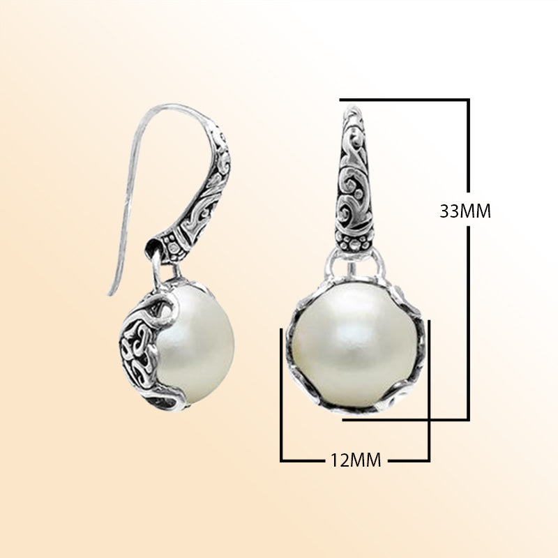 Sterling silver artisan earrings featuring glowing Mabe pearls embraced by ornate Balinese-style silverwork, designed to offer an expressive and elegant look for everyday refined wear.