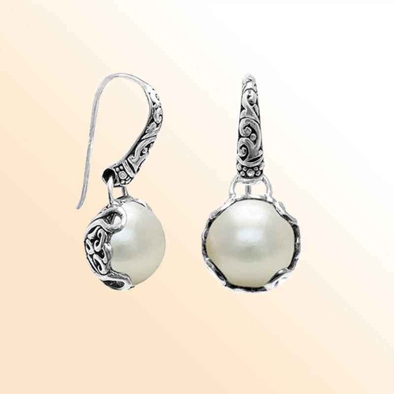 Sterling silver artisan earrings featuring glowing Mabe pearls embraced by ornate Balinese-style silverwork, designed to offer an expressive and elegant look for everyday refined wear.