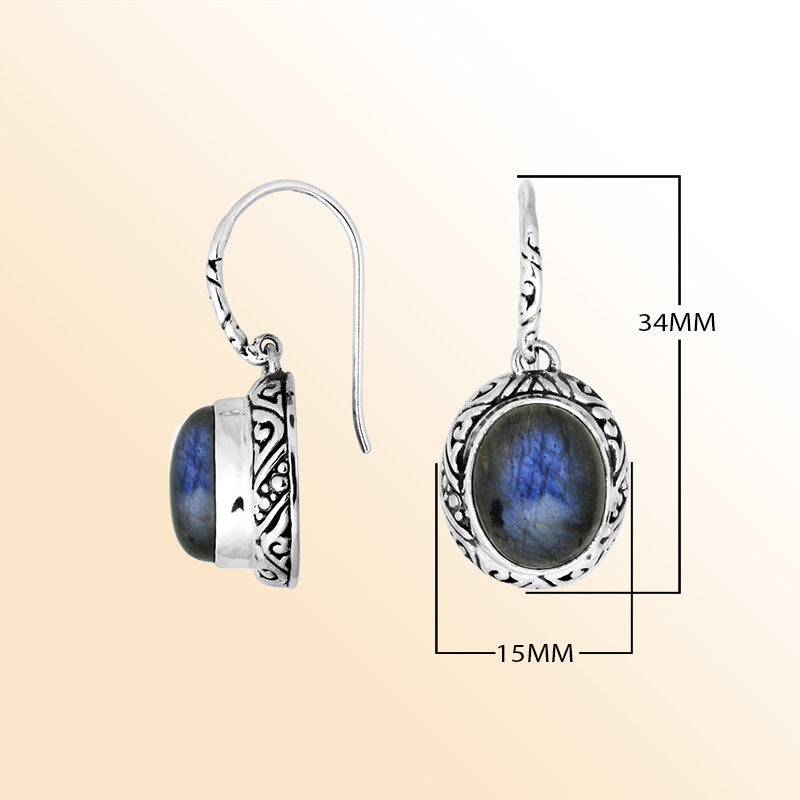 Sterling silver earrings featuring an oval Labradorite cabochon surrounded by artistic carved detailing with an earwire lock, offering luminous color play and handcrafted elegance for everyday wear.