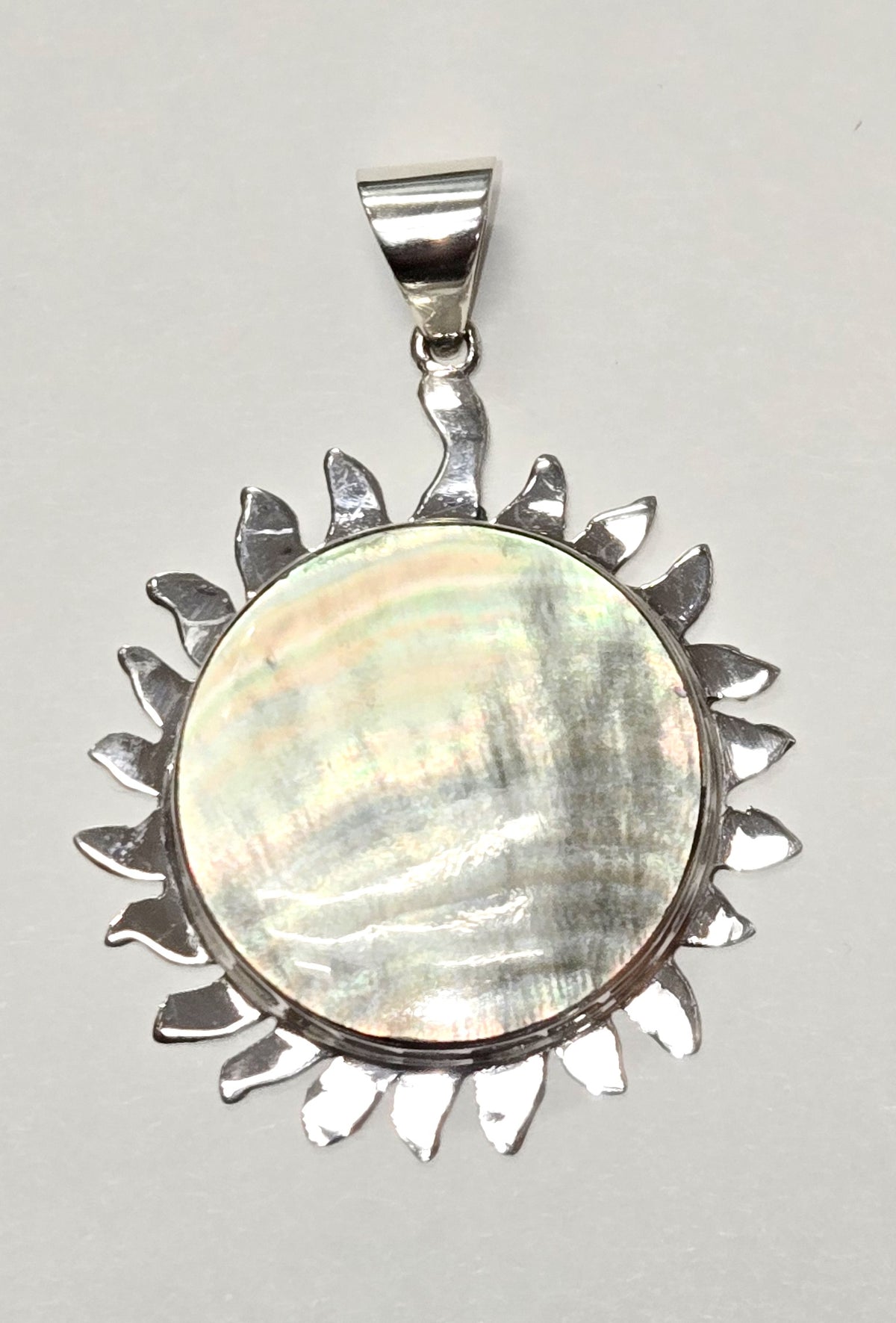 Handcrafted sterling silver sunburst pendant with luminous Jeping Shell center, elegant Bali jewelry design.