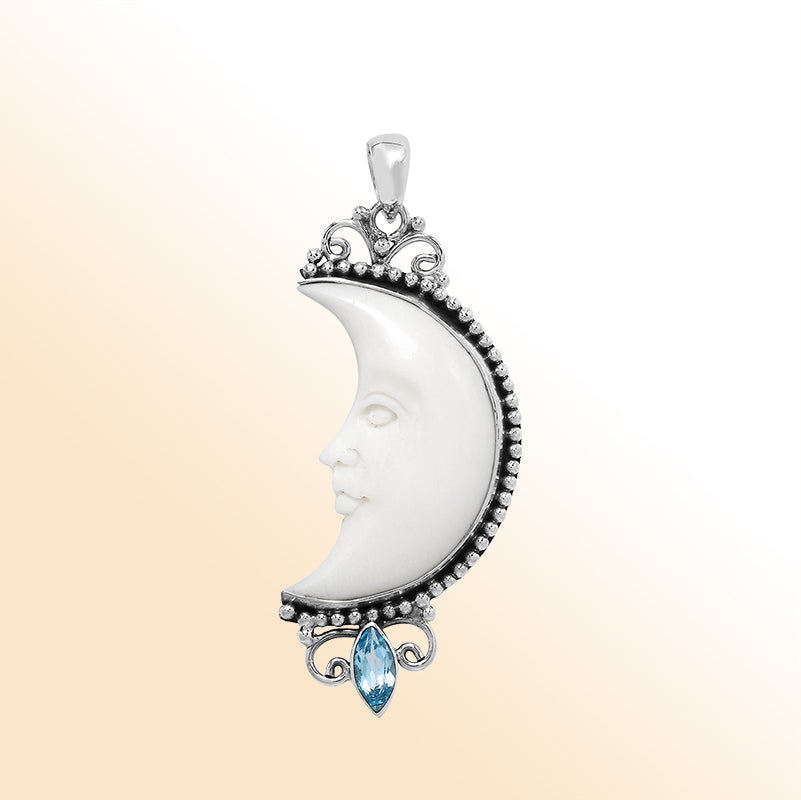 Crescent moon face pendant in sterling silver with carved bone and sparkling blue topaz quartz accent, handmade in Bali.