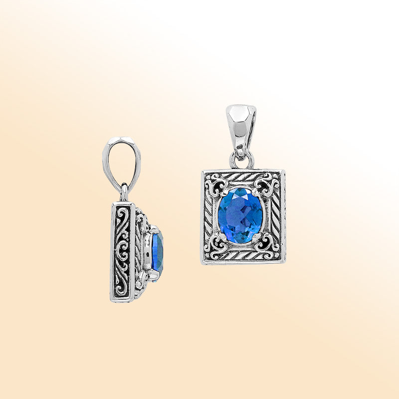 Handcrafted sterling silver pendant with oval blue topaz quartz, ornate swirl engraving, and polished finish showcasing fine Balinese artistry.