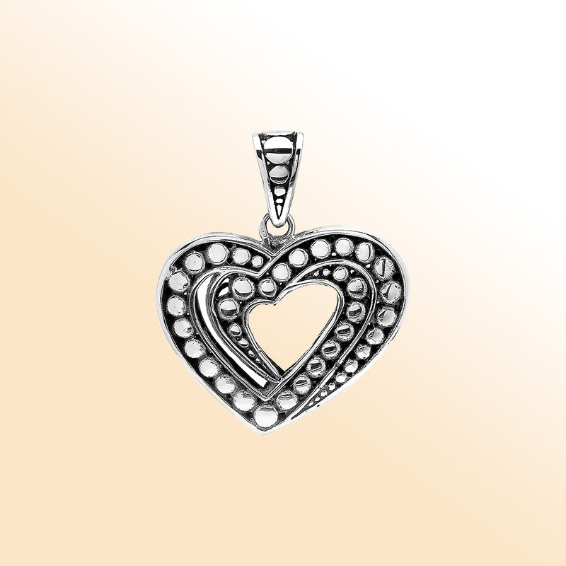 Handcrafted sterling silver heart-shaped pendant with layered open-heart design, dotted engravings, and oxidized Balinese detailing.