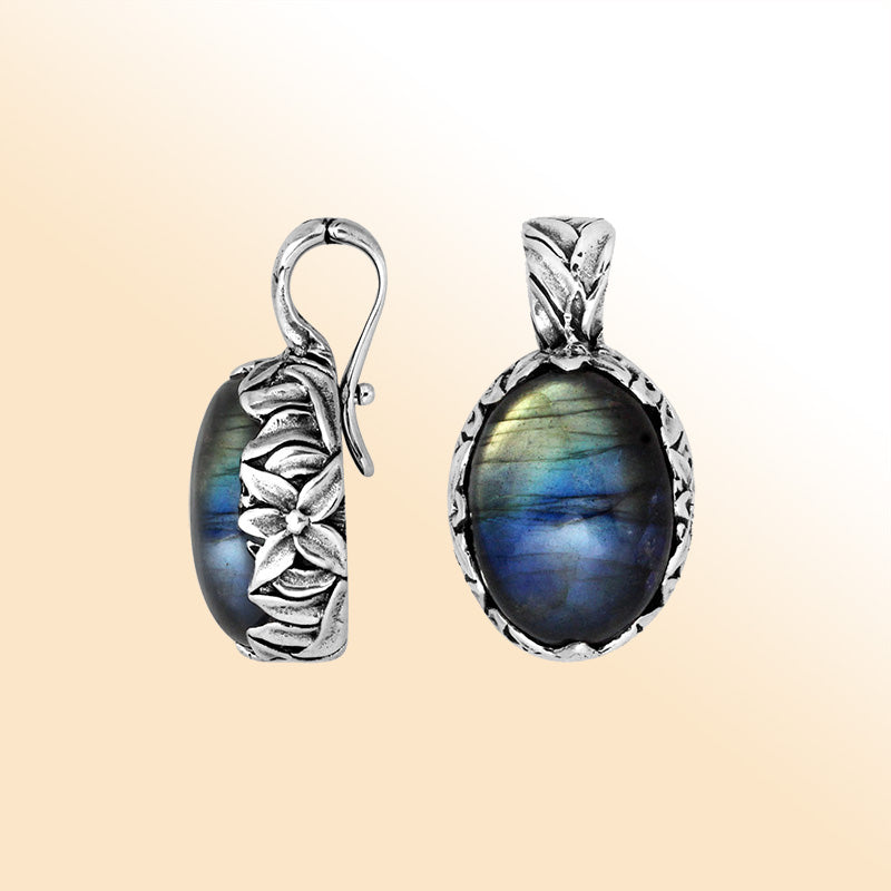 Handcrafted sterling silver oval pendant featuring glowing Labradorite and artistic Balinese floral details.
