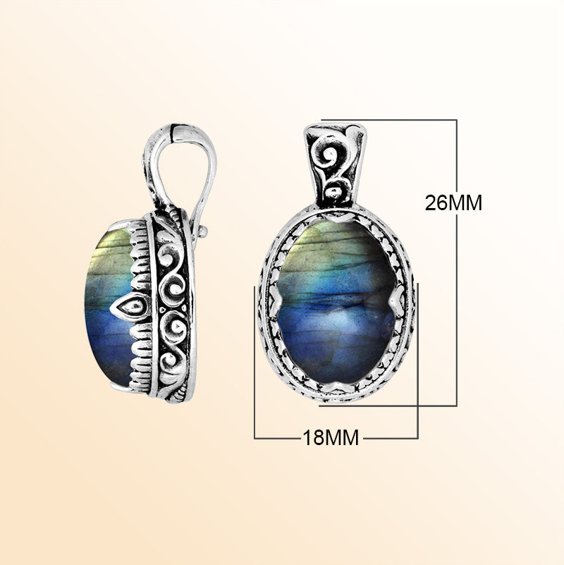 A handcrafted sterling silver pendant showcasing an iridescent Labradorite centerpiece accented with artistic Balinese scroll carvings and a smooth decorative frame for expressive personal styling.