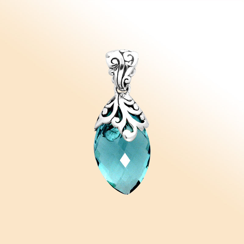 Handcrafted sterling silver marquise pendant featuring a faceted Blue Topaz Quartz centerpiece accentuated with artistic Balinese filigree carvings and a polished decorative frame.