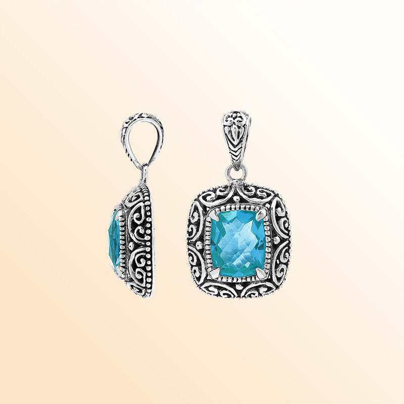 Handcrafted sterling silver cushion pendant featuring a faceted Blue Topaz Quartz centerpiece highlighted by artistic Balinese scroll carvings and a smooth decorative frame.