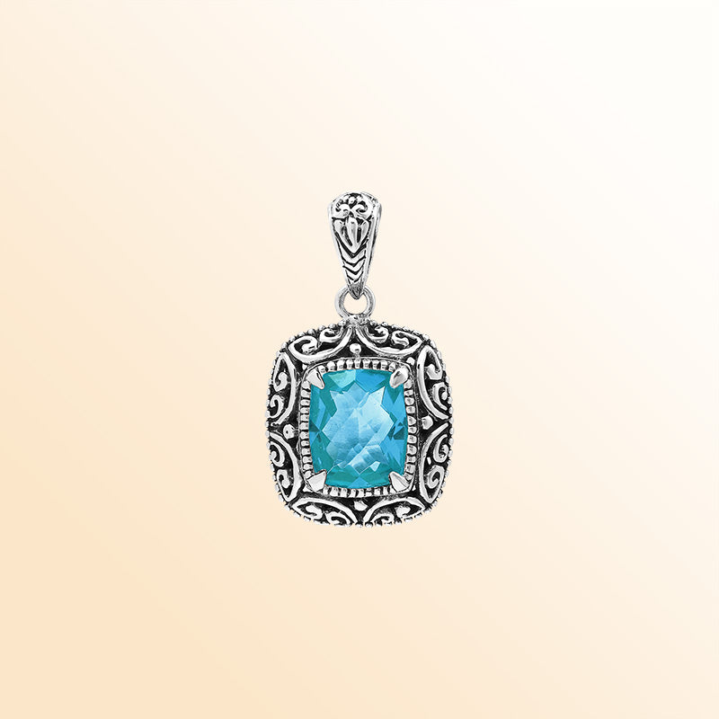 Handcrafted sterling silver cushion pendant featuring a faceted Blue Topaz Quartz centerpiece highlighted by artistic Balinese scroll carvings and a smooth decorative frame.