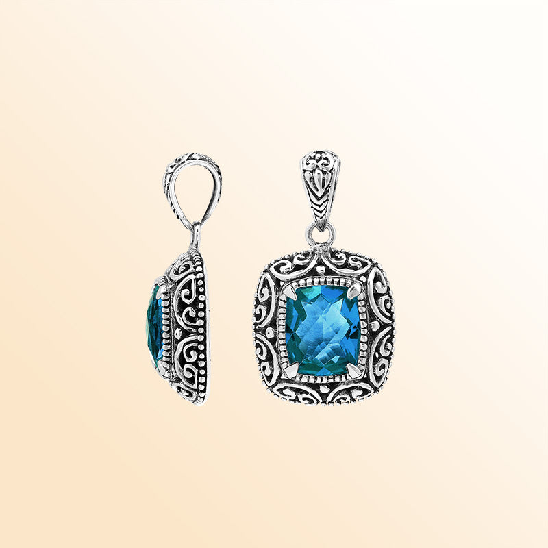 Handcrafted sterling silver cushion pendant showcasing a faceted London Blue Topaz Quartz centerpiece with artistic Balinese scroll carvings and a polished decorative frame.