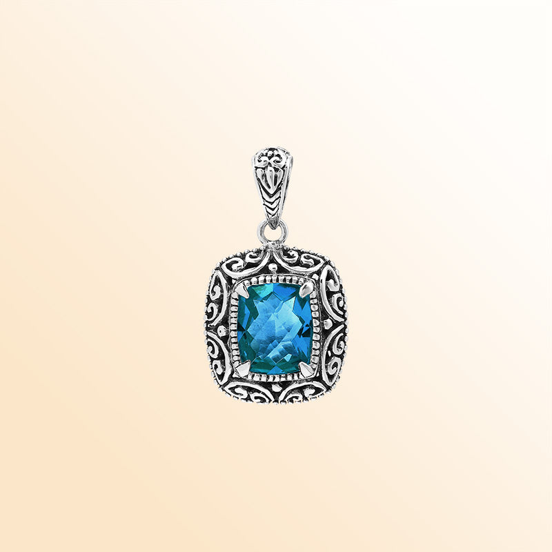 Handcrafted sterling silver cushion pendant showcasing a faceted London Blue Topaz Quartz centerpiece with artistic Balinese scroll carvings and a polished decorative frame.