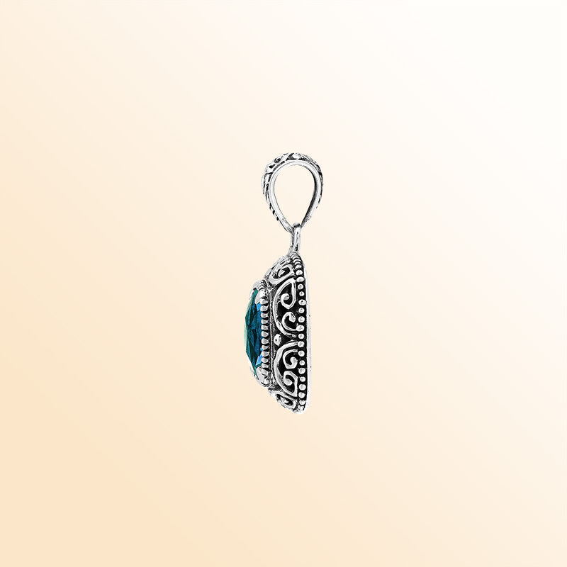 Handcrafted sterling silver cushion pendant showcasing a faceted London Blue Topaz Quartz centerpiece with artistic Balinese scroll carvings and a polished decorative frame.