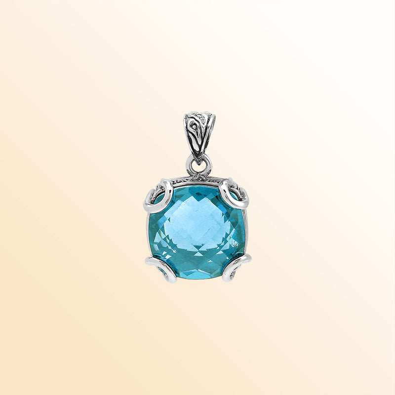 Handcrafted sterling silver cushion pendant featuring a faceted Blue Topaz Quartz centerpiece highlighted by artistic prong work and Balinese carved detailing.