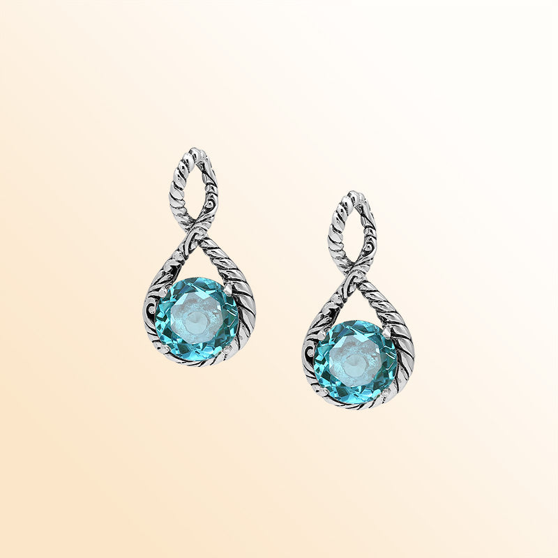 Handcrafted sterling silver twisted loop pendant featuring a faceted Blue Topaz Quartz centerpiece with artistic engraved detailing and Balinese styling.