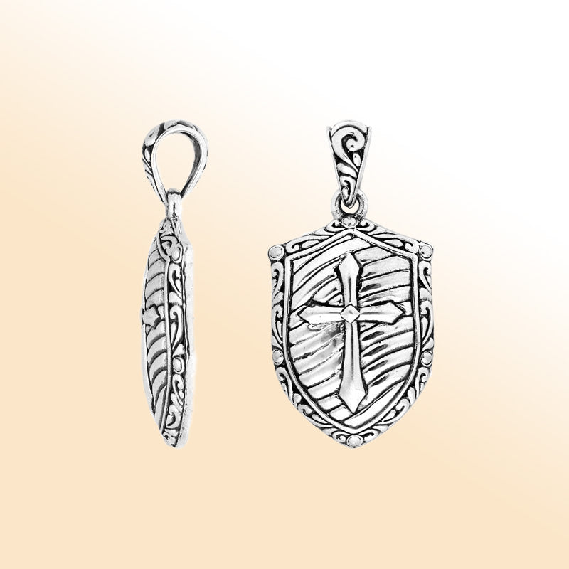 Artistic sterling silver shield pendant featuring an engraved cross design with textured background, polished borders, and expressive handcrafted-inspired detailing for modern jewelry lovers