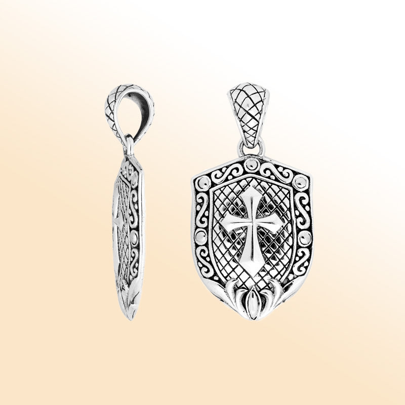 Artistic sterling silver shield pendant featuring an engraved cross with decorative scrollwork and a textured background for expressive modern handcrafted-inspired jewelry styling