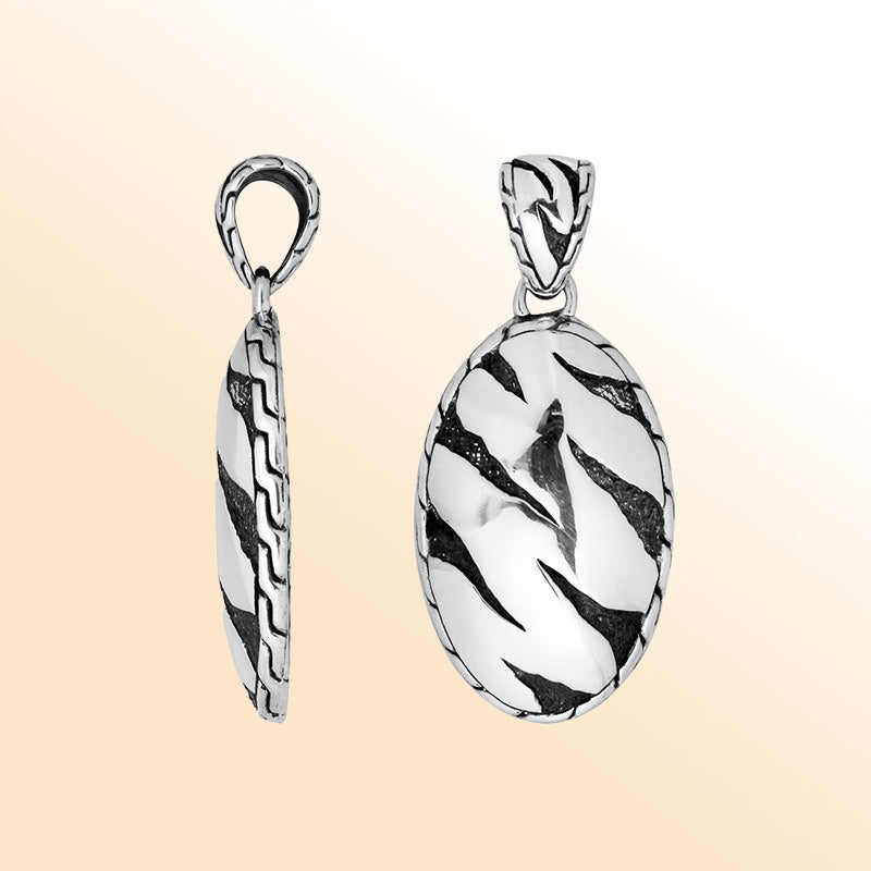 Artistic sterling silver oval pendant with abstract carved black design.