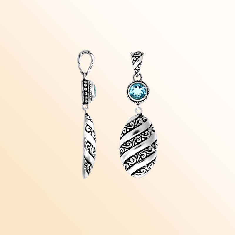 A handcrafted Silver Overlay Over Copper pendant featuring a vivid blue topaz quartz stone, artistic Balinese spiral carvings, oxidized textures, and polished detailing for elegant everyday or special-occasion wear.