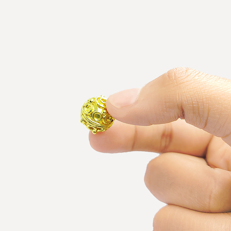Round handcrafted India bead with 18K gold overlay over copper featuring decorative circular pattern.