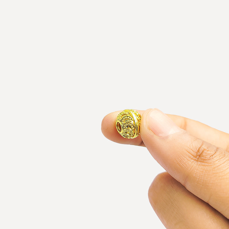 Handcrafted 18K gold overlay embossed copper round bead from India with swirl and dot patterns for jewelry making.