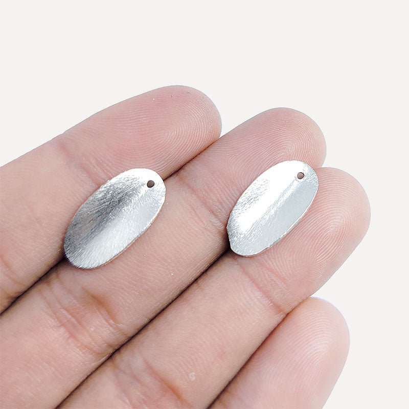Silver overlay over copper oval drop charm with textured finish handcrafted in India