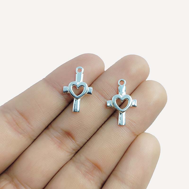 Polished silver overlay cross charm with heart cutout crafted from silver overlay over copper in India.