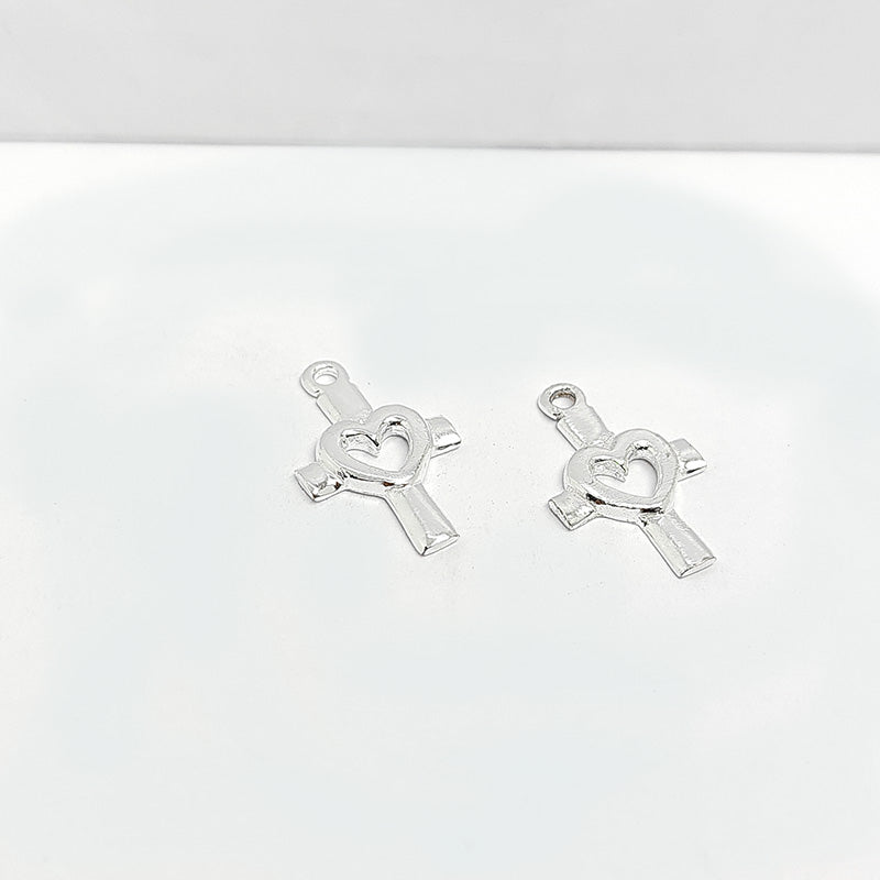 Polished silver overlay cross charm with heart cutout crafted from silver overlay over copper in India.