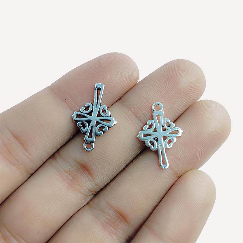 Polished silver overlay decorative cross pendant crafted from silver overlay over copper with scroll detailing in India.