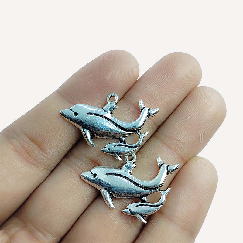 Polished silver overlay dolphin pendant crafted from silver overlay over copper featuring large and small dolphin design in India.