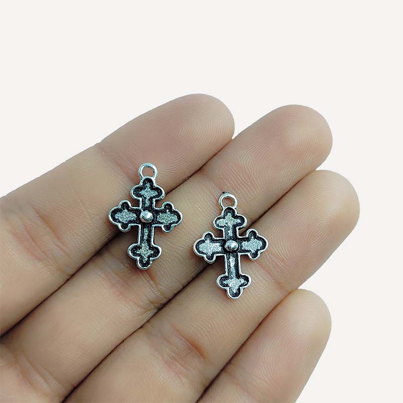 Polished silver overlay cross pendant with raised center detail crafted from silver overlay over copper in India.