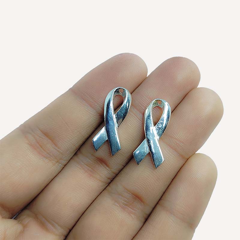 Polished silver overlay awareness ribbon pendant crafted from silver overlay over copper in India.