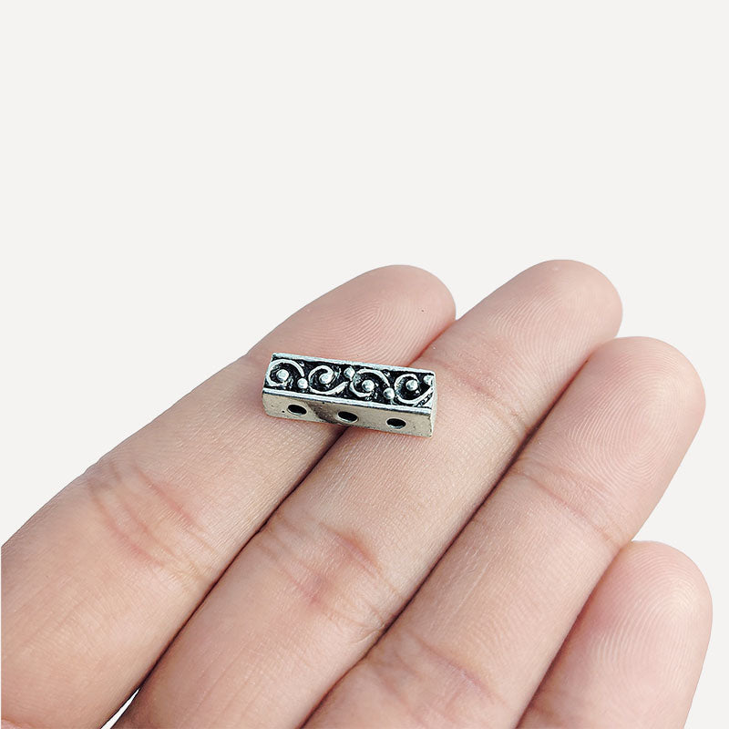 Handcrafted silver overlay over copper spacer bar with three holes and swirl pattern from India for jewelry making